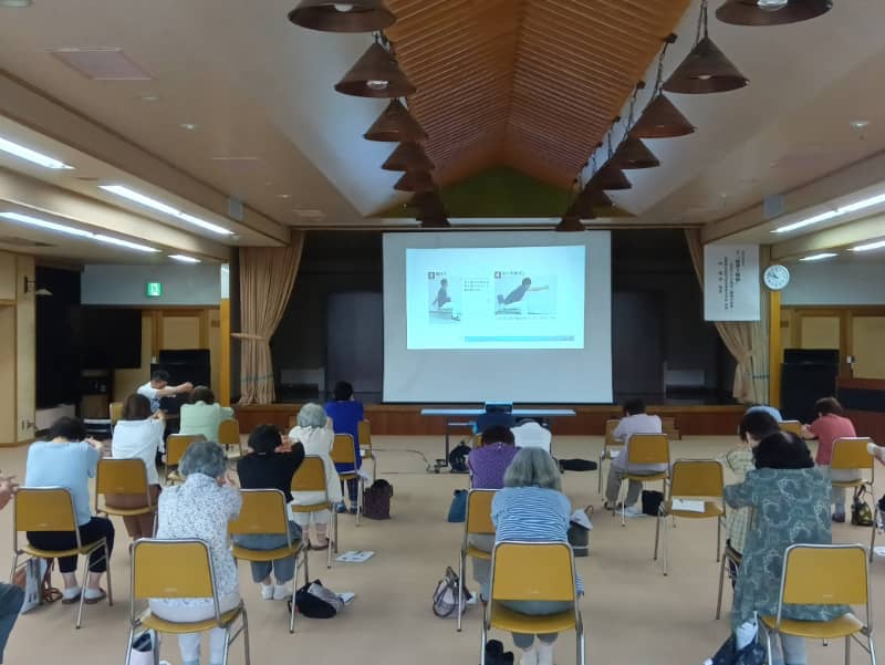 健康と睡眠に関する講演会の様子。参加者が講演を聞き入る中、スクリーンには睡眠に関する情報が表示されている。