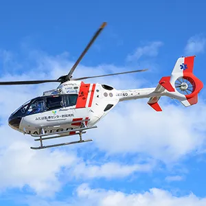 福島県立医科大学の救急医療用ヘリコプターが青空を背景に飛行している様子。