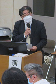 講義台でマイクを持ち発表を行っている様子。