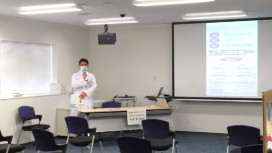 会議室でプレゼンテーションを行う白衣を着た男性
