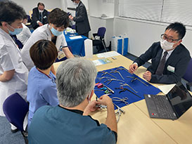 数人がテーブルを囲み医療器具について話している様子。