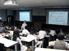 教室で大学生たちがスライドを使った講義を受けている