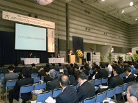多くの人が座っている会場で行われている講演会