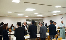 会議室で立ち話をするビジネススーツ姿の人々