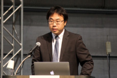 スーツを着た男性が講演会で演説中