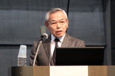 壇上でスーツを着た男性が講演を行っている様子