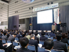 多くの人が会場でプレゼンテーションを聴いている