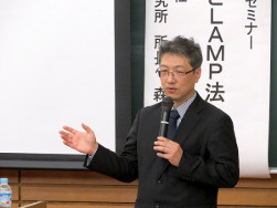 男性が講義室でマイクを持ちプレゼン中