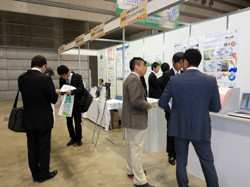 展示会で複数の男性がブースで話をしている様子