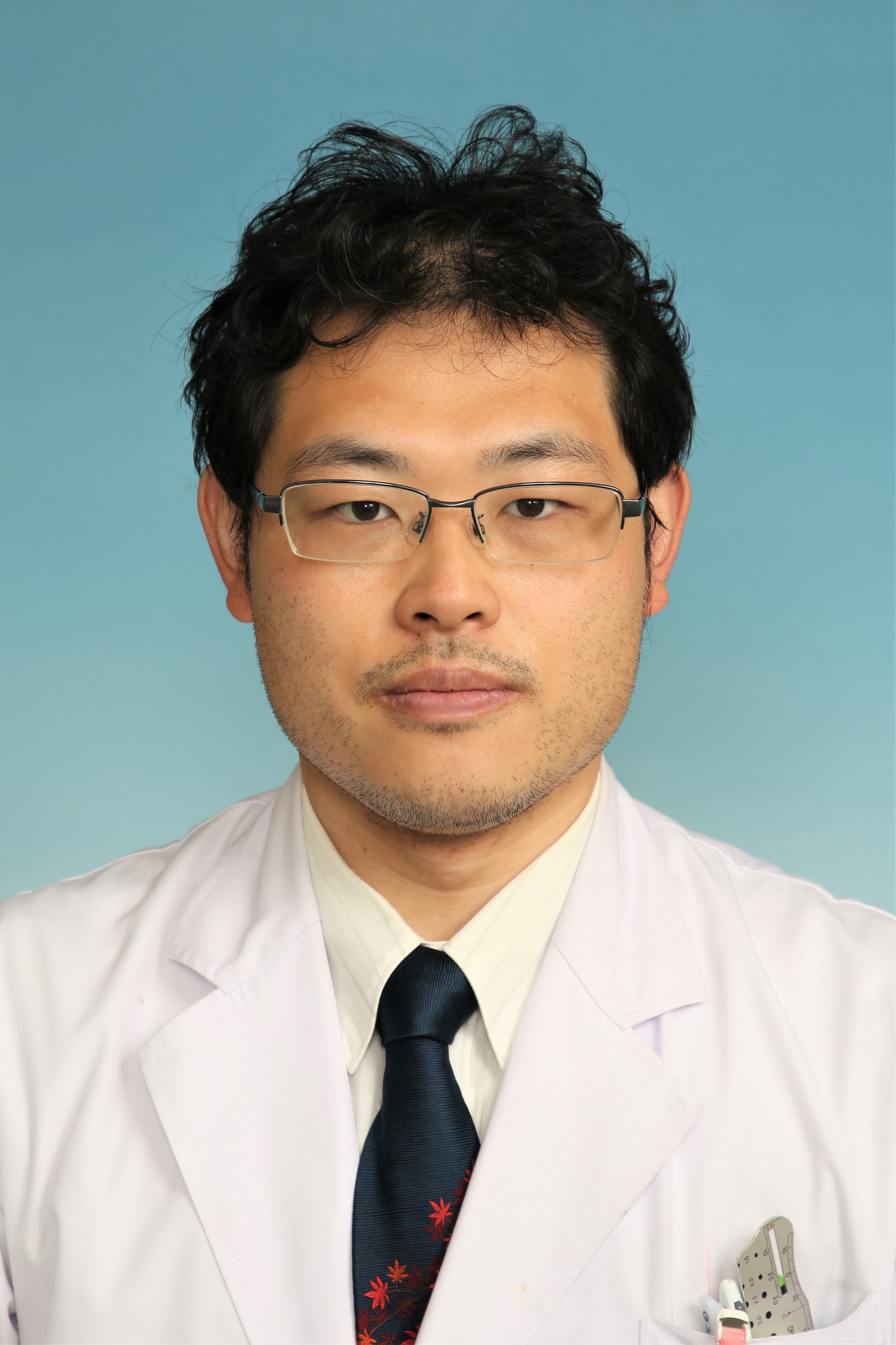 眼科学講座の本庄純一郎助教のポートレート。白衣にネクタイを着用しまじめな表情で正面を見ている