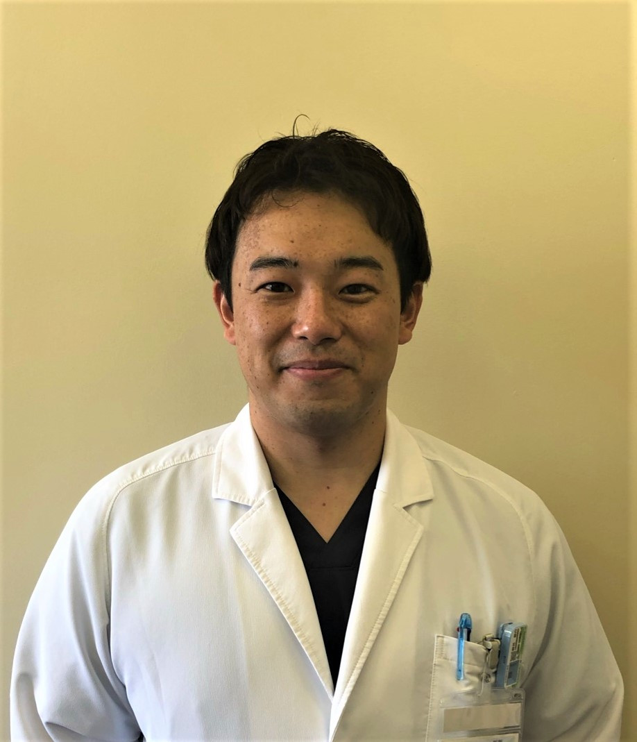 泌尿器科学講座の桐花悠介病院助手のポートレート。白衣を着て微笑んでいる姿。