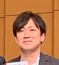 放射線健康管理学講座の阿部暁樹講座等研究員のポートレート。正面を向いて微笑んでいる姿。