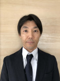 医療白衣を着た男性のポートレート、青い背景の前で真剣な表情をしている。