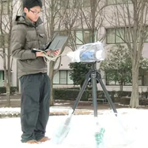 傾いた漁船が草むらに埋もれ、周囲には電柱が立つ風景。