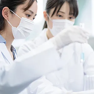 研究室で実験を行う2人の女性研究者が、試験管を使っている様子。
