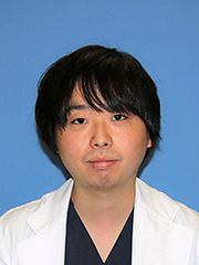 福島県立医科大学の助手、小河原崚氏のポートレート写真。白衣を着て微笑む姿。