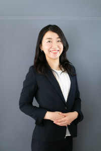 福島県立医科大学の腫瘍内科学講座主任教授、佐治重衡氏のポートレート。白衣を着用し、背景には書類や小物が並ぶ。