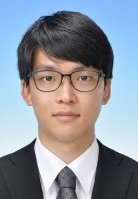 福島県立医科大学の腫瘍内科学講座主任教授、佐治重衡氏のポートレート。白衣を着用し、背景には書類や小物が並ぶ。