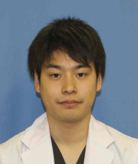 福島県立医科大学の腫瘍内科学講座主任教授、佐治重衡氏のポートレート。白衣を着用し、背景には書類や小物が並ぶ。