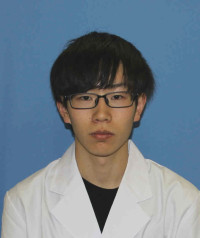 福島県立医科大学の腫瘍内科学講座主任教授、佐治重衡氏のポートレート。白衣を着用し、背景には書類や小物が並ぶ。