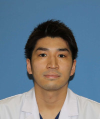 医療白衣を着た男性のポートレート、青い背景の前で真剣な表情をしている。