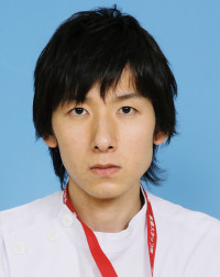 福島県立医科大学の腫瘍内科学講座主任教授、佐治重衡氏のポートレート。白衣を着用し、背景には書類や小物が並ぶ。