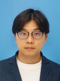 医療白衣を着た男性のポートレート、青い背景の前で真剣な表情をしている。