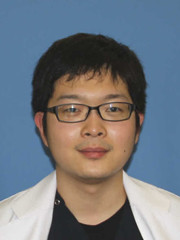 福島県立医科大学の助手、小河原崚氏のポートレート写真。白衣を着て微笑む姿。