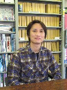 福島県立医科大学の苅谷慶喜講師が書棚の前で微笑んでいる写真。
