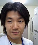 医療現場で白衣を着た男性のポートレート。背景には医療機器が見える。