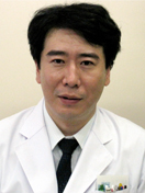 福島県立医科大学の助教、國井泰人氏が白衣を着て微笑んでいるポートレート。