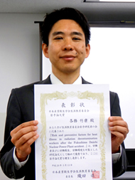 福島県立医科大学の各務竹康講師が表彰状を持って微笑んでいる写真。