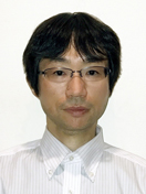 医学部の研究者、櫛田信博氏のポートレート。白いシャツと眼鏡を着用。