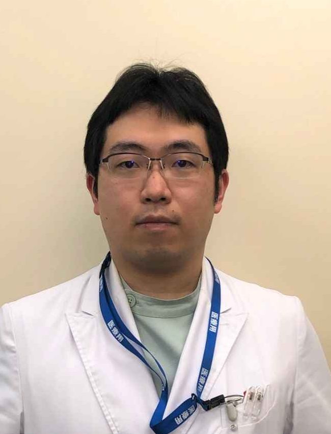 医療白衣を着た男性がカメラに向かって立っているポートレート。