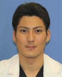 医療用白衣を着た男性のポートレート写真。背景は青色。