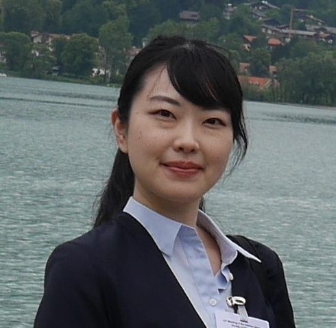 福島県立医科大学の入江絹子さんが湖の前で微笑んでいる写真。