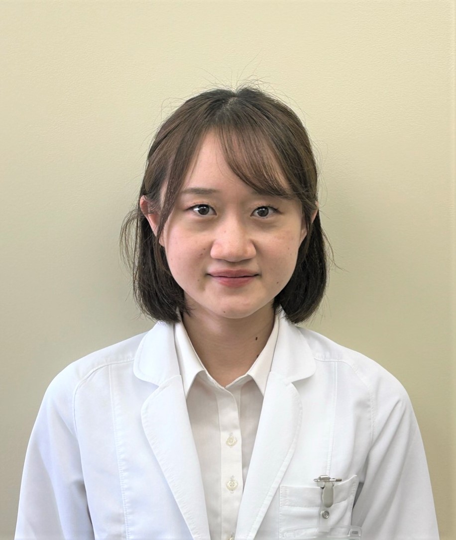 医療白衣を着た女性が微笑んでいるポートレート。背景は淡い色合いの壁。