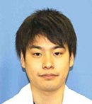 医療白衣を着た男性のポートレート、青い背景の前で微笑んでいる。
