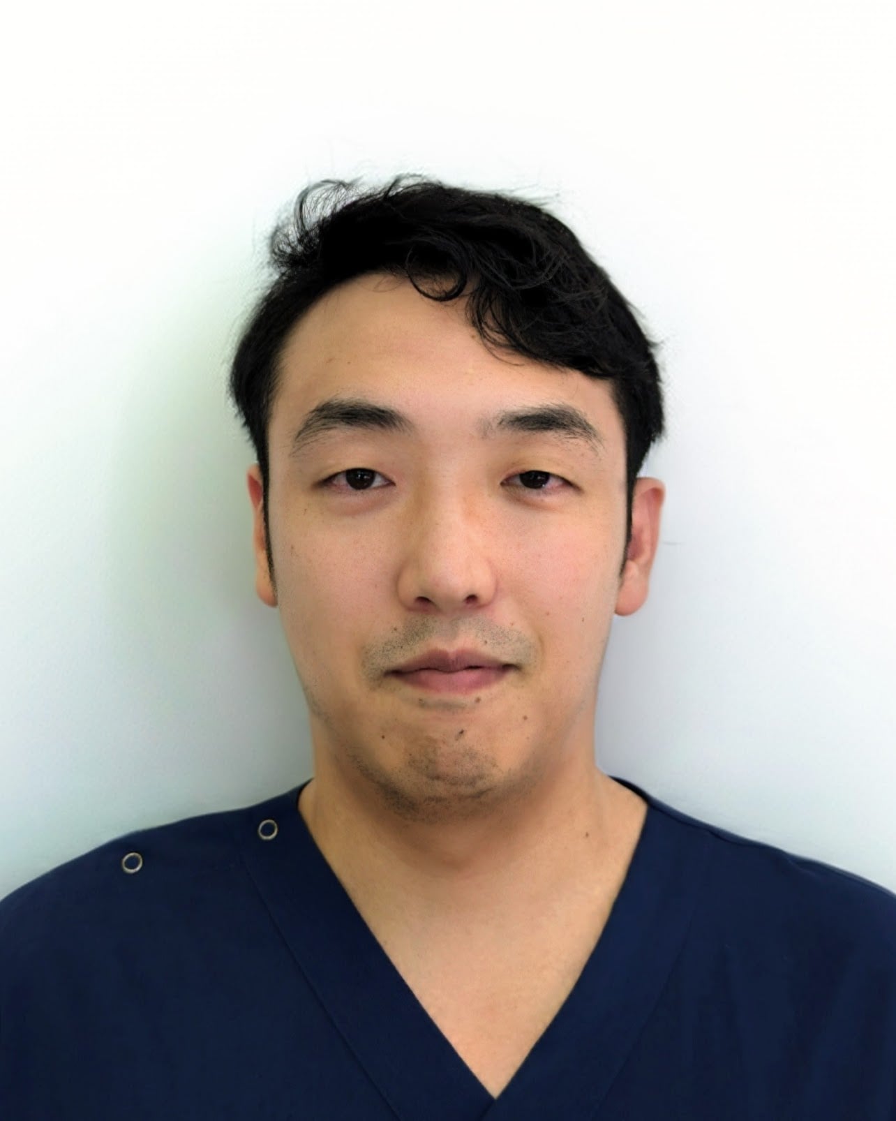 福島県立医科大学の助手、小河原崚氏のポートレート写真。白衣を着て微笑む姿。