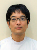 福島県立医科大学の武藤哲史博士のポートレート。白衣を着て、真剣な表情でカメラを見つめている。