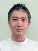 福島県立医科大学の助教、郷勇人氏のポートレート写真。白衣を着用し、真剣な表情でカメラを見つめている。