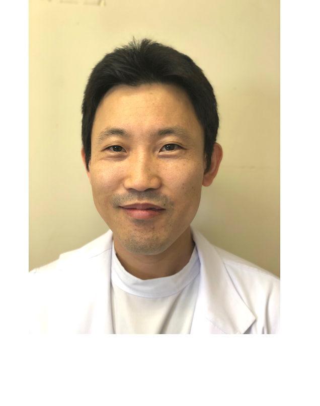 医療白衣を着た男性のポートレート。穏やかな表情でカメラを見つめている。