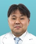 医療白衣を着た男性の医師が微笑んでいるポートレート。背景は淡い青色。
