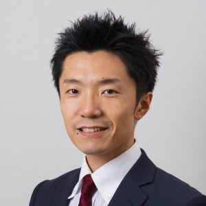 福島県立医科大学の栗田宜明准教授がスーツ姿で微笑んでいるポートレート。