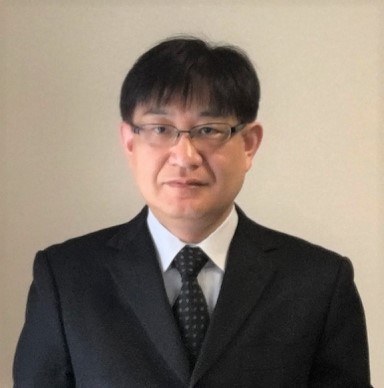 池田和彦教授がスーツを着てカメラに向かって微笑んでいるポートレート。