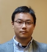 医学部の大学院生である林学さんのポートレート。眼鏡をかけ、スーツ姿で真剣な表情を浮かべている。