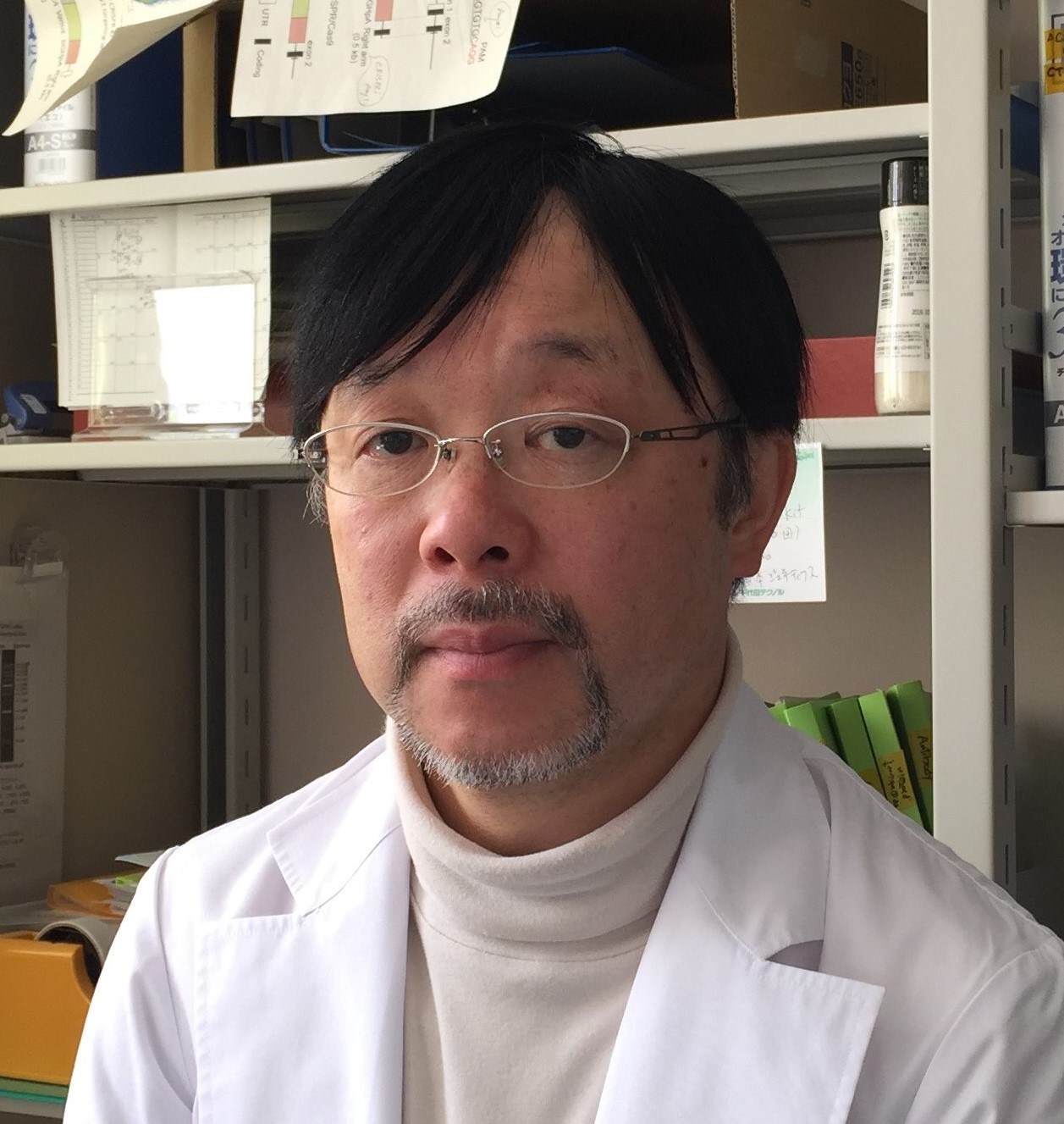 福島県立医科大学の准教授、関亦正幸氏が白衣を着て研究室で微笑んでいる写真。