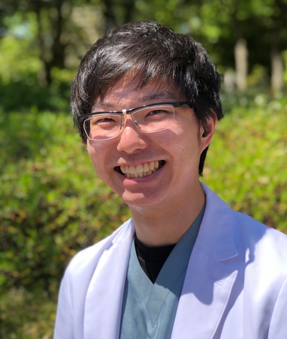 福島県立医科大学の学生が笑顔で外でポーズをとっている写真。背景には緑の植物が広がっている。