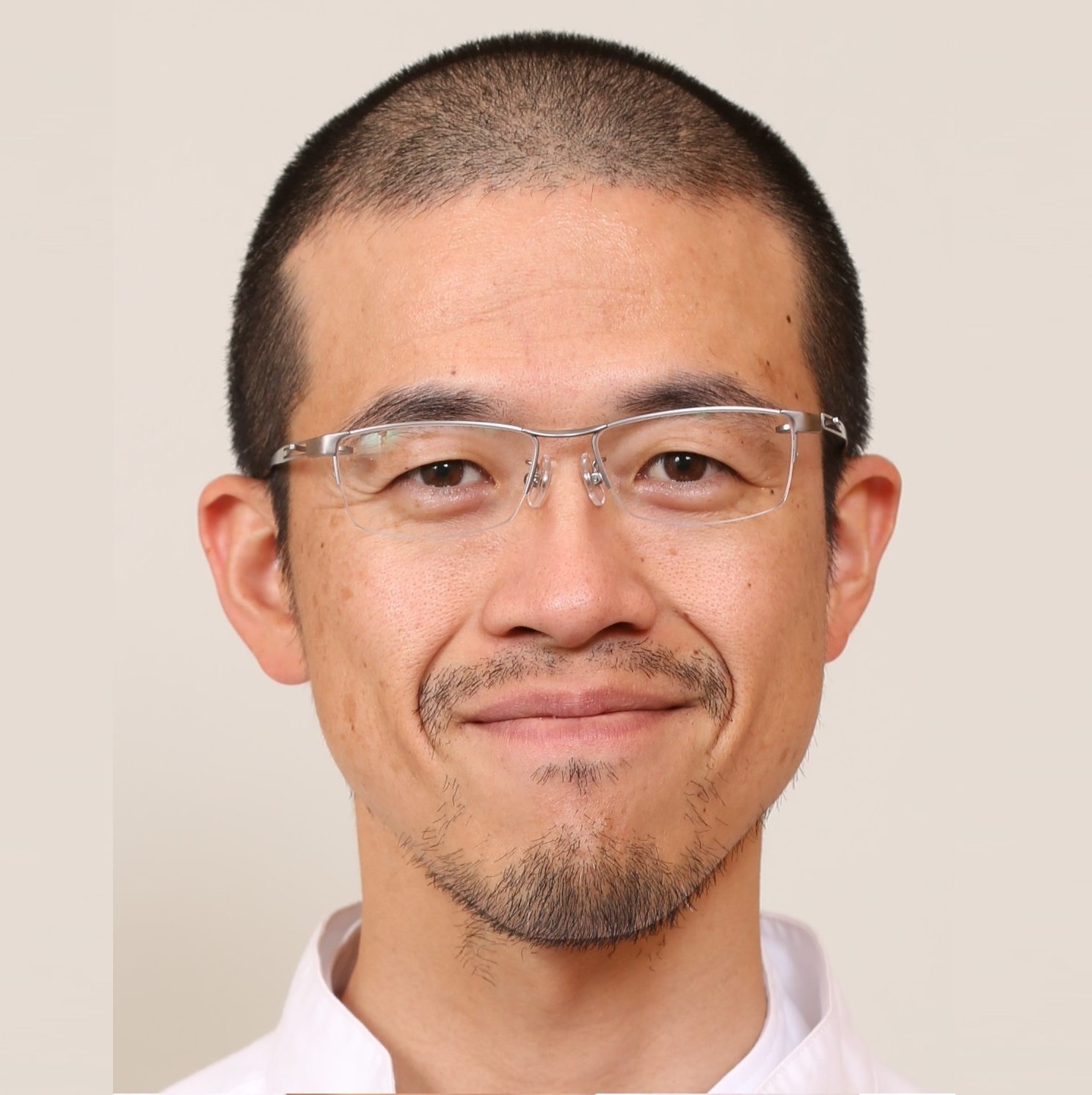 医師の岩味健一郎氏が白衣を着て微笑んでいるポートレート。