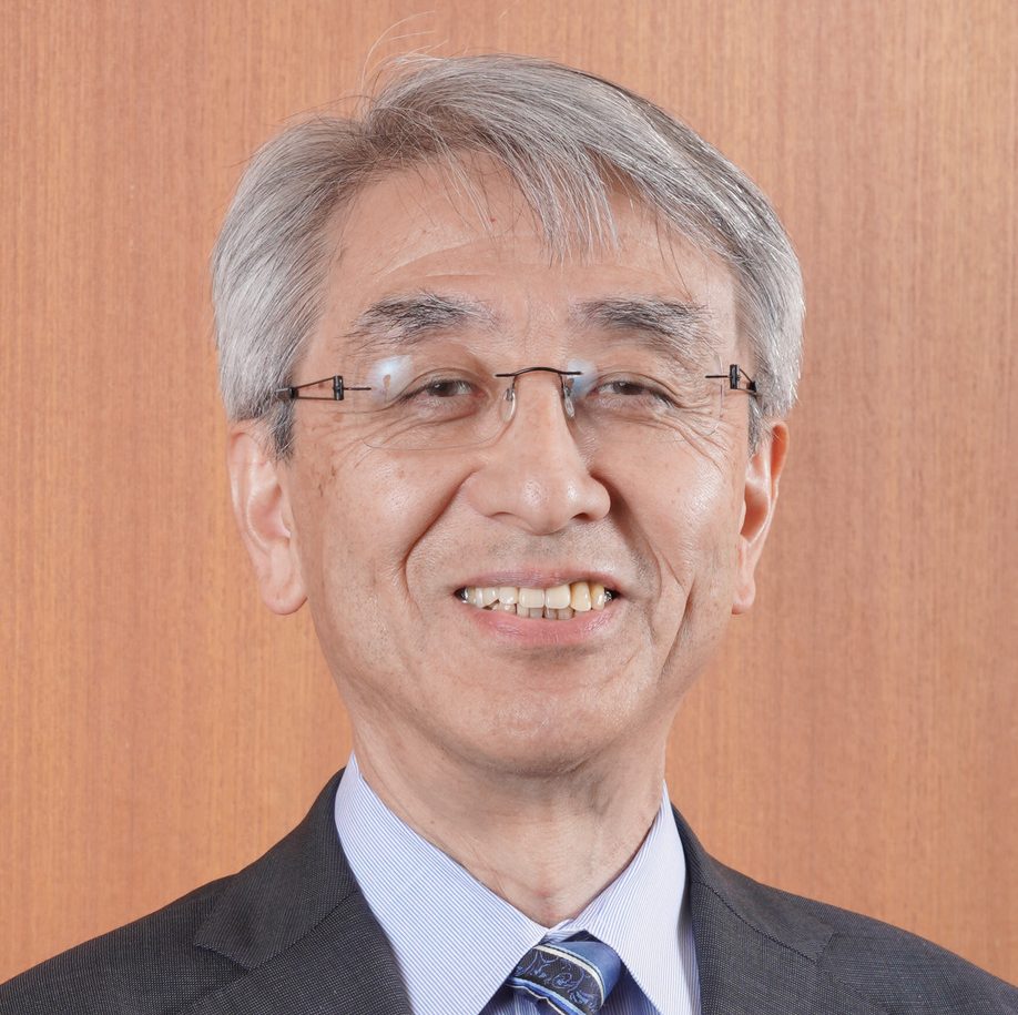 齋藤清教授が微笑みながらカメラを見つめるポートレート。背景は木目調の壁。